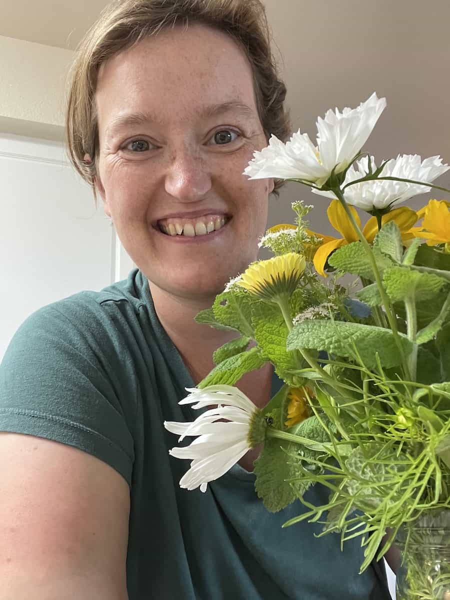 woman smiling while standing next to bouquet of flowers